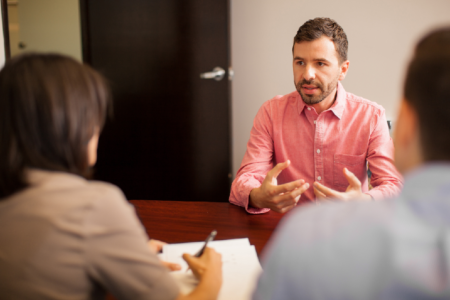 a man talking to a woman over a table taking notes