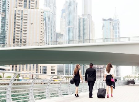 office workers walking beside a river in a city
