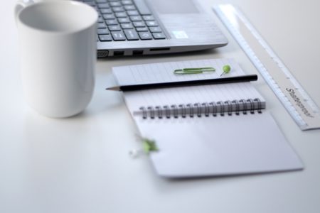 a desk with keyboard, notepad, and coffee mug