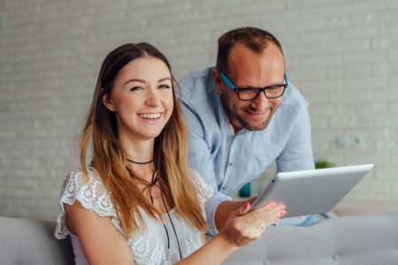 a happy man and woman looking at a tablet
