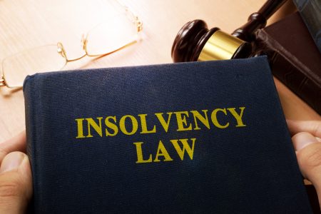 Insolvency law book on a desk over a gavel.