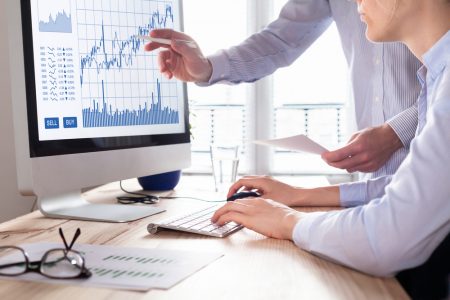 Two individuals in front of a computer looking at a graph.