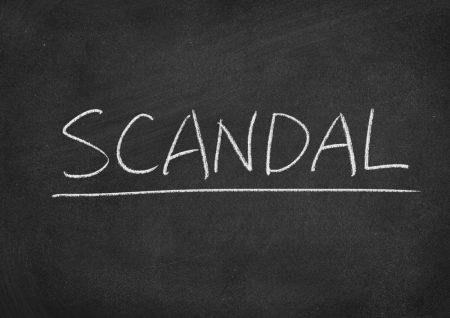 The word "SCANDAL" written on a chalkboard.