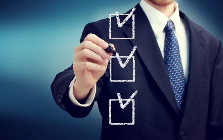 Businessman ticking off a checklist on the key features of the best claims management software.