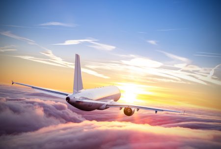 Flight claims concept - airplane flying above clouds in sunset light.