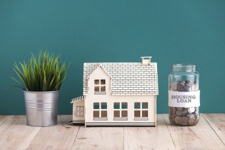 Mortgage miscalculation claims concept with miniature house and jar of coins labeled as "housing loans".