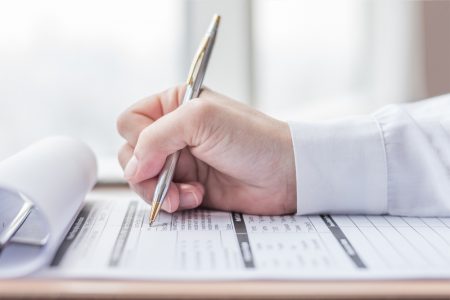 Person's hand writing on a form from claims management companies.