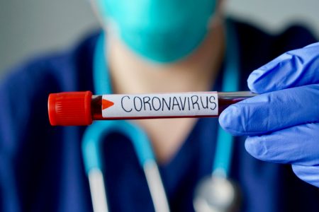 Nurse wearing respirator mask holding a positive blood test result for Coronavirus.