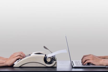 typewriter and laptop back to back on a desk