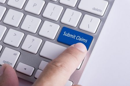 a finger pressing a blue submit claims button on a keyboard - a post discussing best claims management software
